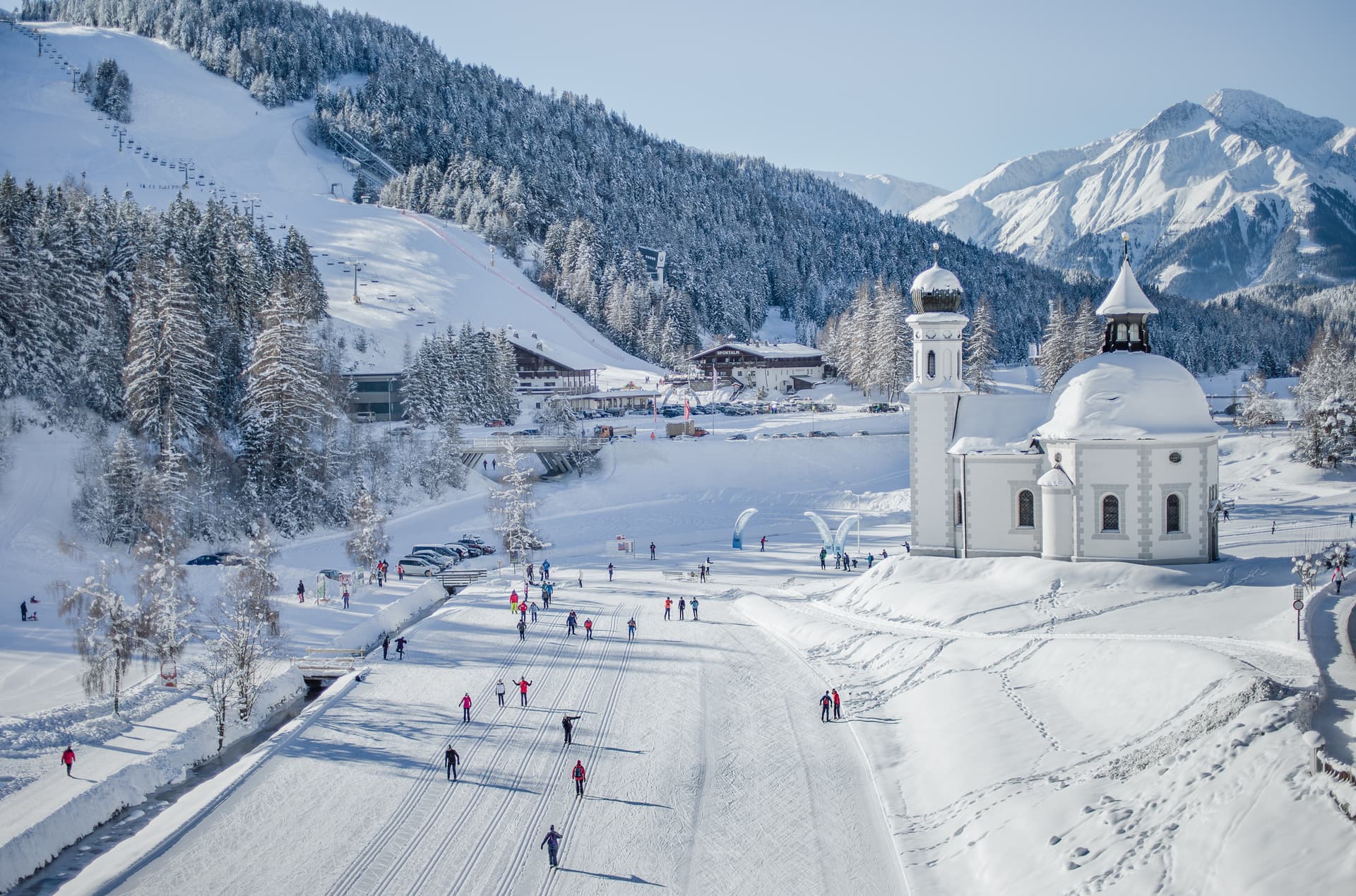 Skiiers skiing past traditional church in Seefeld ski resort
